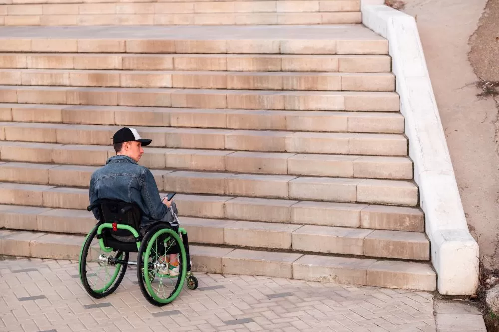 Un jeune handicapé en fauteuil roulant ne pouvant pas monter les escaliers