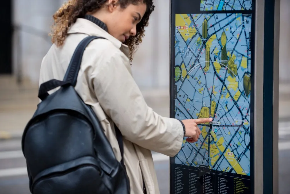 Plan urbain interactif Femme consultant un plan sur un panneau d’information urbain